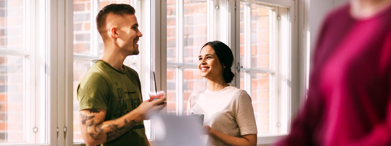 Two people talking next to the window and smiling