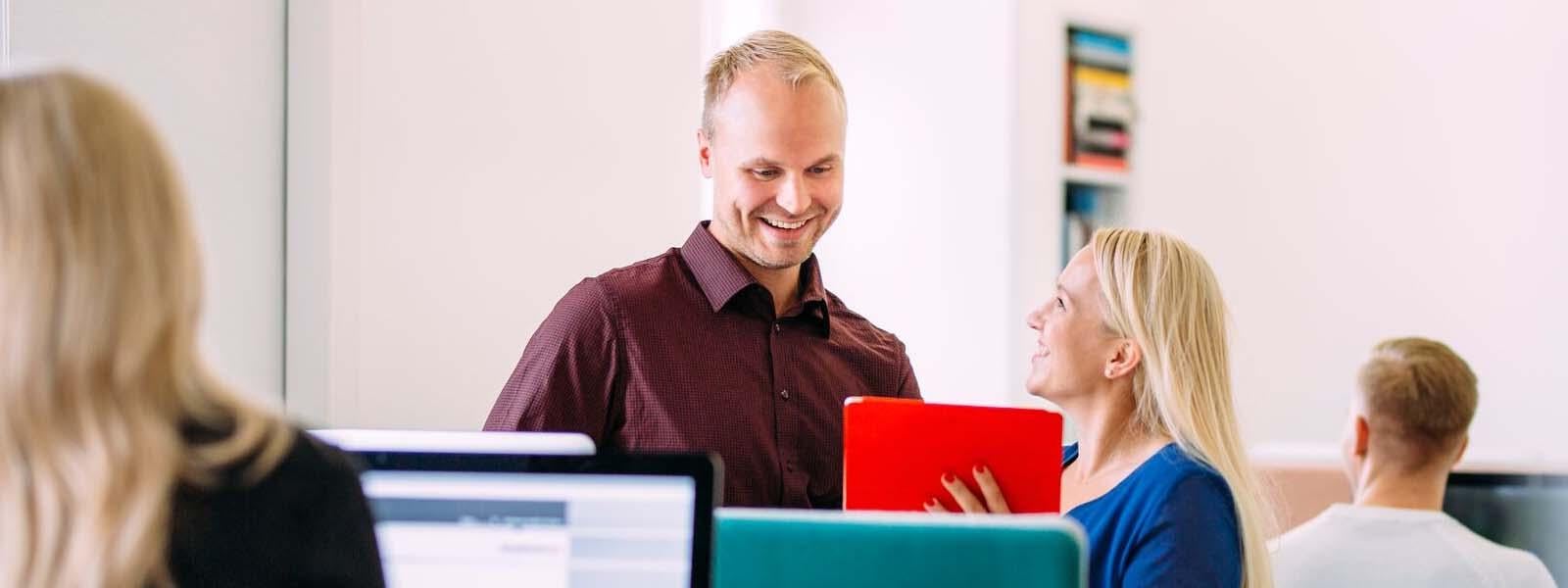 Woman with red folder talking to a man and smiling