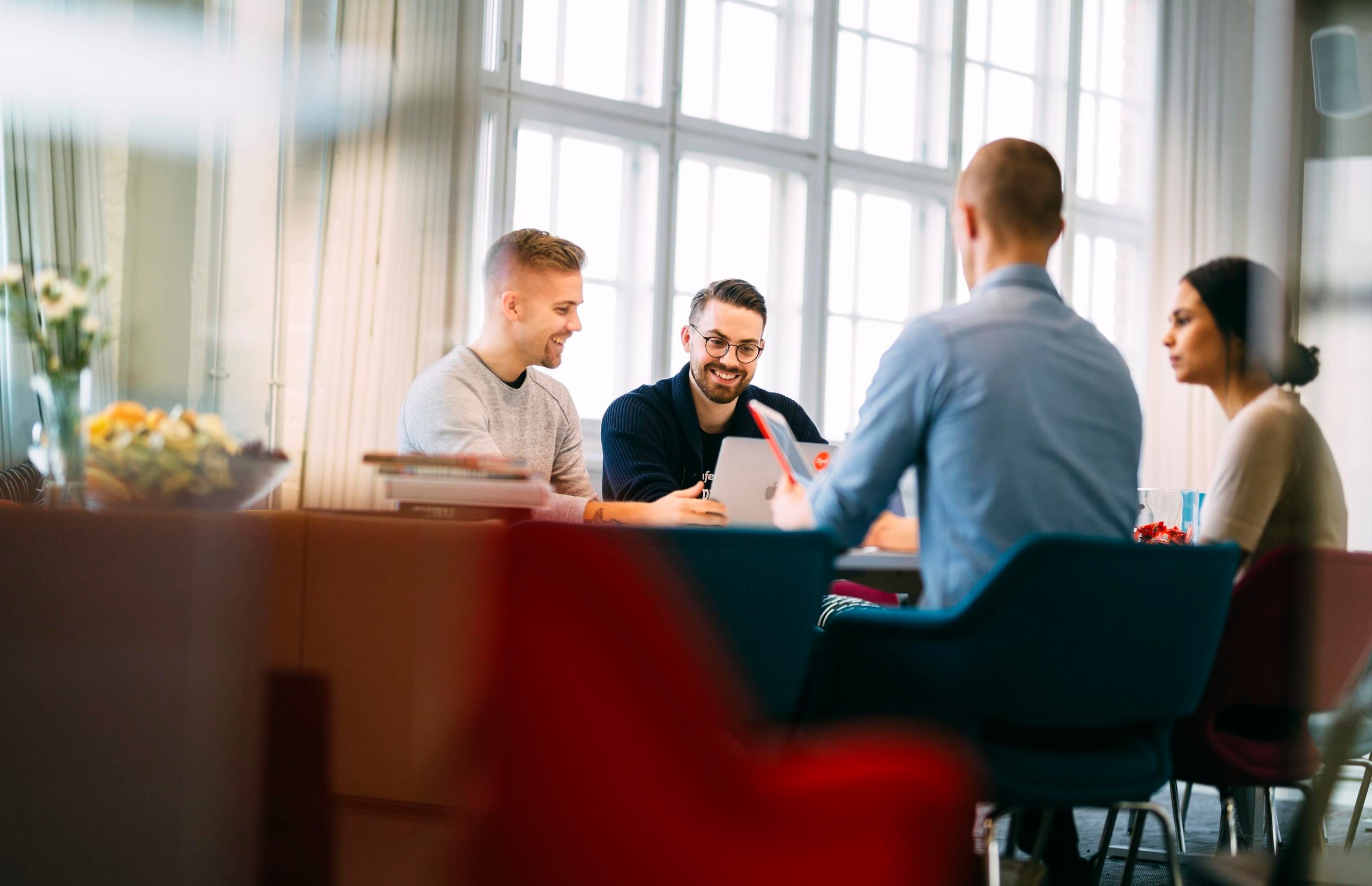 Four people sitting at the office table and smiling
